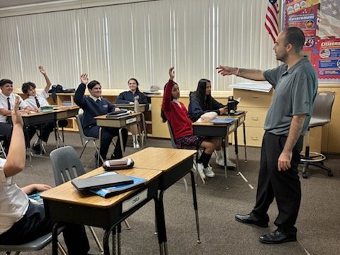 A teacher calls on SSFP middle school students raising their hands in class