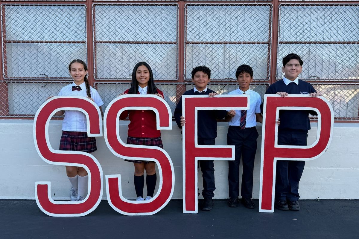 Five SSFP students in uniform standing behind large red SSFP letters on campus